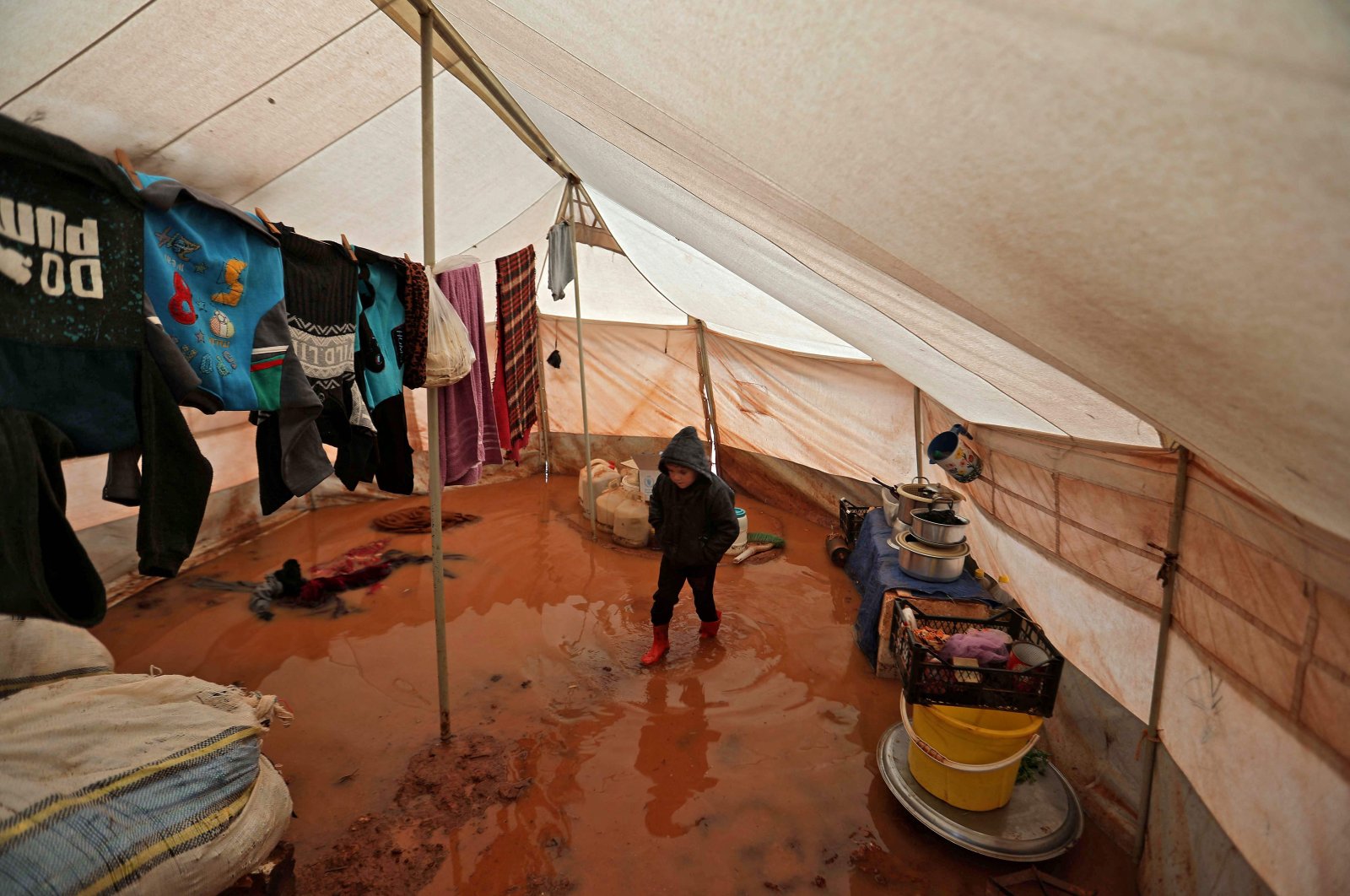 A child walks inside a flooded tent at a camp by the village of Killi, near Bab al-Hawa by the border with Turkey, in Syria&#039;s Idlib province, Dec. 20, 2021. (AFP Photo)