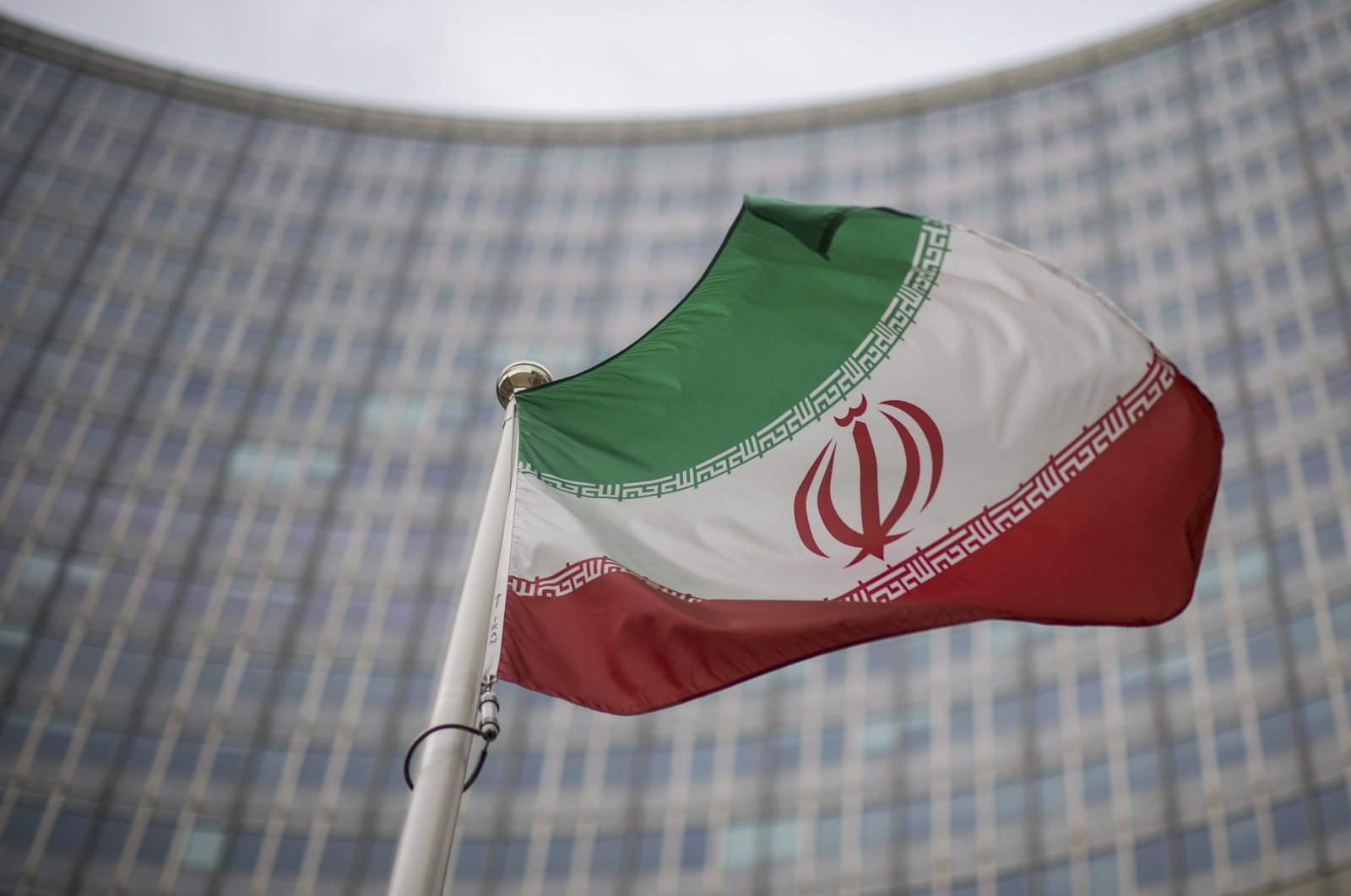A national flag of Iran waves in front of the building of the International Atomic Energy Agency, IAEA, in Vienna, Austria, Dec. 17, 2021. (AP Photo)