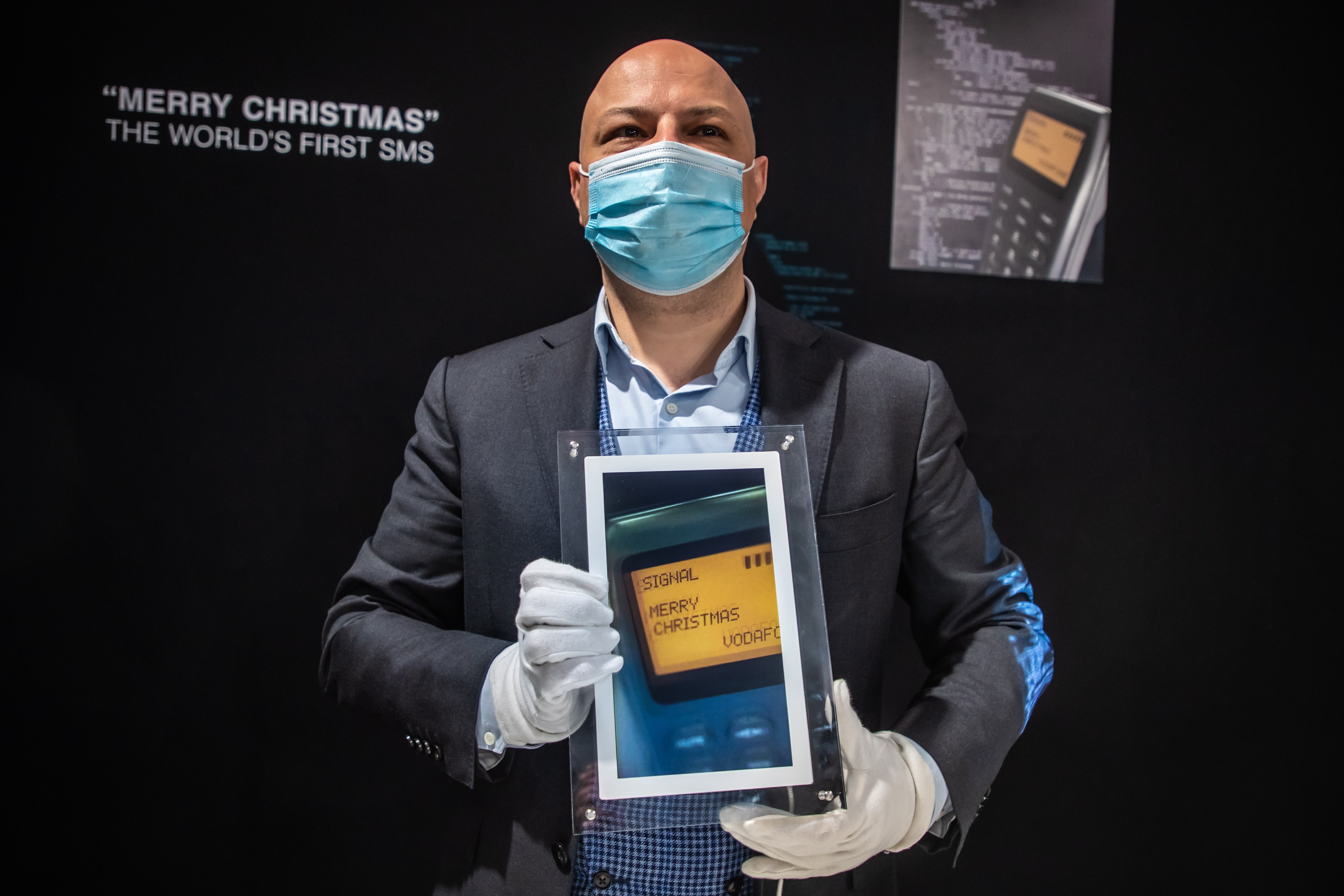 An Aguttes auction house staff shows a digital frame displaying the message "Merry Christmas," the first SMS in history, Paris, France, Dec. 21, 2021. (EPA Photo)
