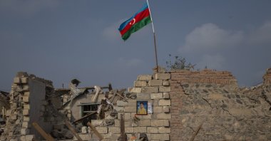 A picture of a boy killed in Armenian attacks hangs on the wall of a damaged building as an Azerbaijani flag waves on the rubble above, in Ganja, Azerbaijan, Nov. 5, 2020. (AA Photo)