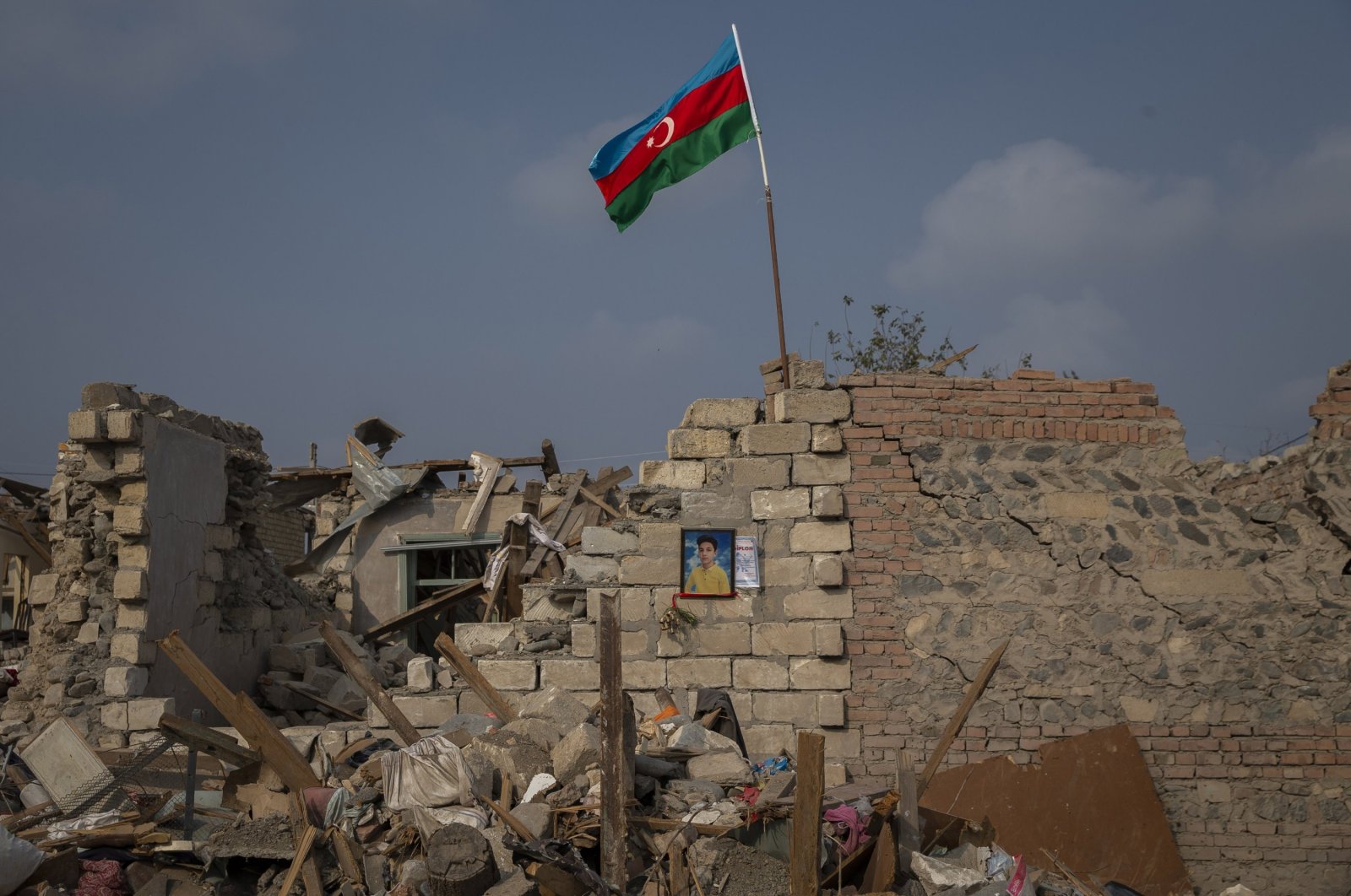A picture of a boy killed in Armenian attacks hangs on the wall of a damaged building as an Azerbaijani flag waves on the rubble above, in Ganja, Azerbaijan, Nov. 5, 2020. (AA Photo)