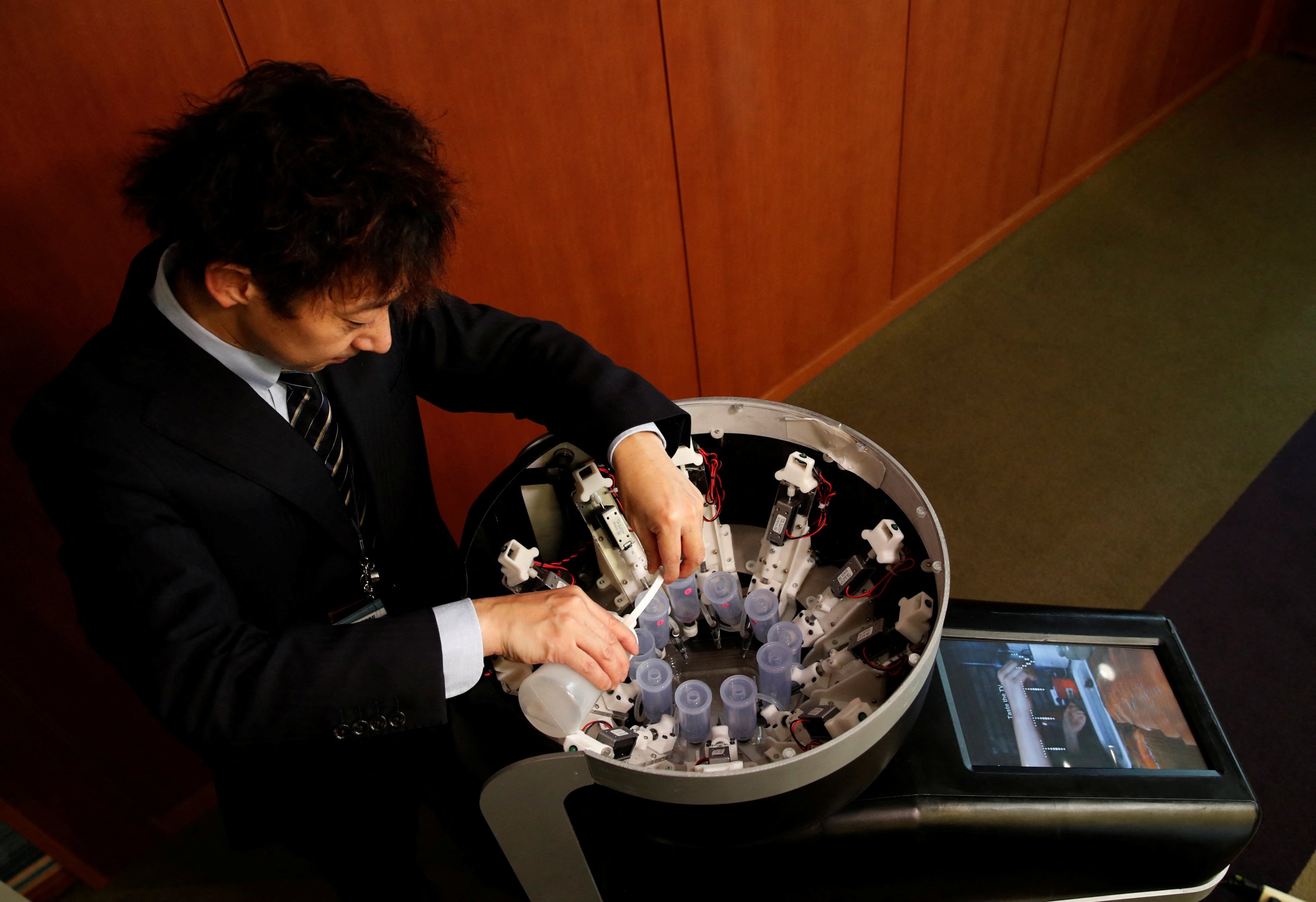 Meiji University professor Homei Miyashita fills flavor canisters as he demonstrates Taste the TV (TTTV), a prototype lickable TV screen that can imitate the flavors of various foods, at the university in Tokyo, Japan, Dec. 22, 2021. (Reuters Photo) 