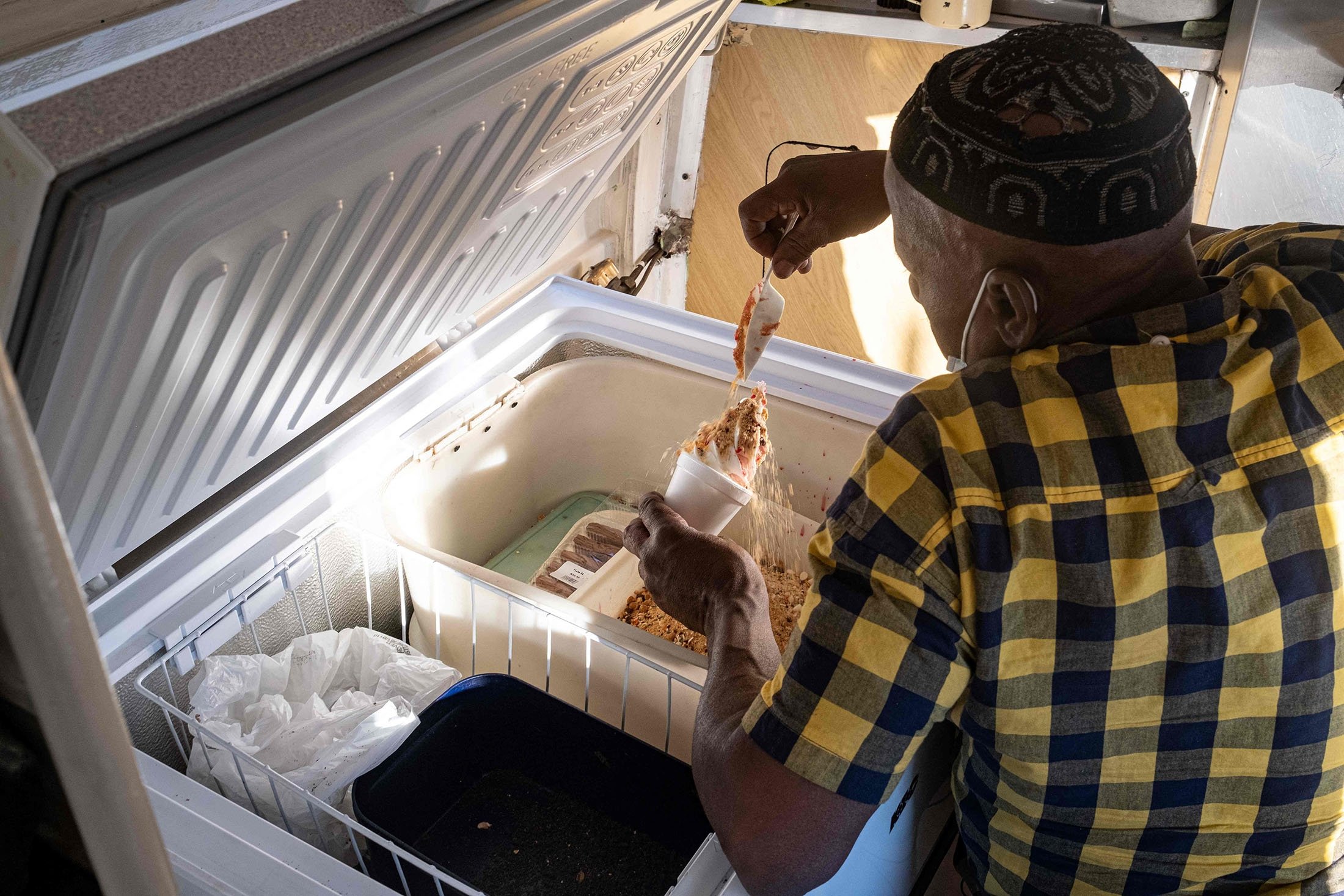 The owner of an ice cream truck, Sipho Mtshali, adds toppings to an ice cream cup for a clustomer in Soweto, South Africa, Nov. 19, 2021. (AFP Photo)