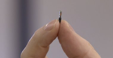 Hannes Sjoblad, director of DSruptive Subdermals, holds an implant between his fingers in Stockholm, Sweden, Dec. 20, 2021. (AFP Photo)