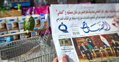 A man reads a local newspaper in the Libyan capital Tripoli, on Dec. 23, 2021, with an article on its front page about the postponement of the country's presidential elections. (AFP Photo)
