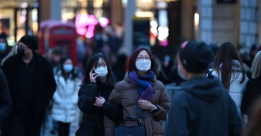 Shoppers wearing face coverings to combat the spread of COVID-19, pass through the Covent Garden area of London on Dec. 21, 2021. (AFP Photo)