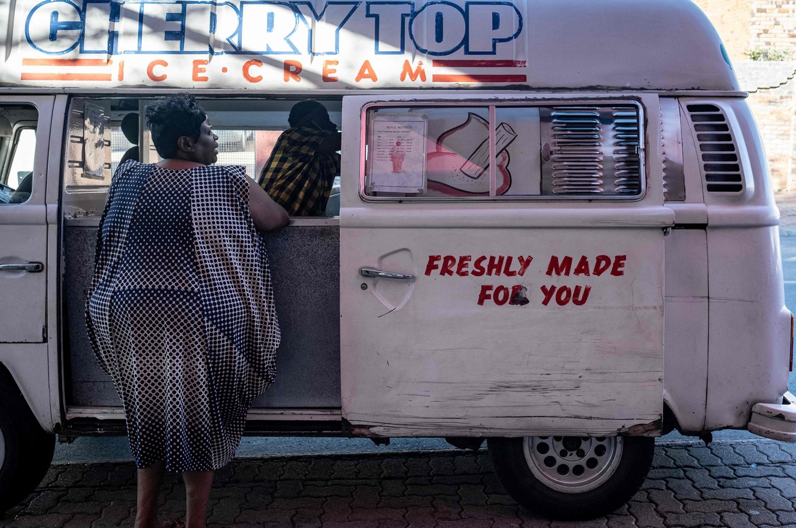 A resident buys ice cream from Sipho Mtshali&#039;s ice cream truck in Soweto, South Africa, Nov. 19, 2021. (AFP Photo)