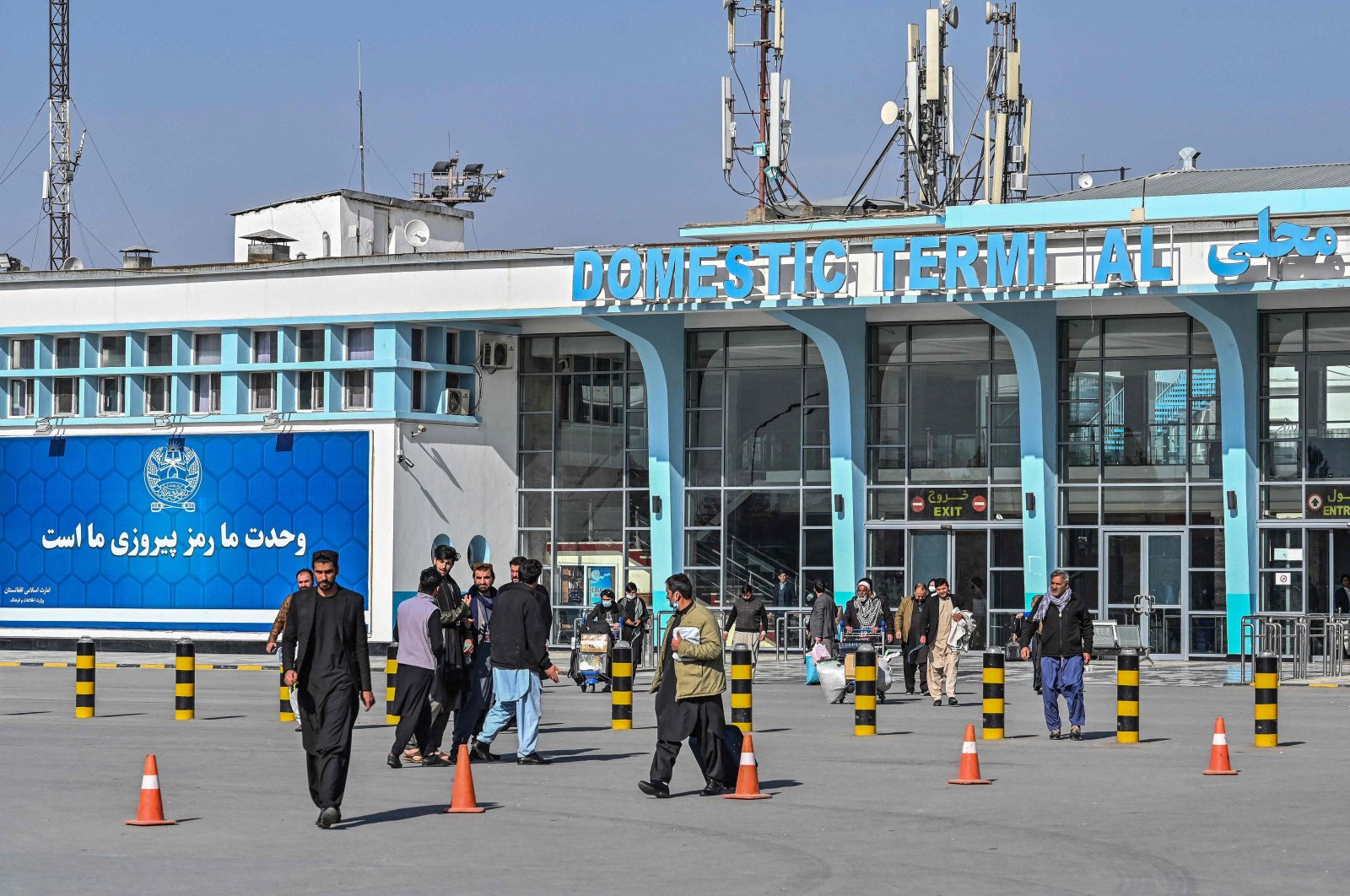 Afghan people walk near the exit gate of the Kabul airport in Kabul on November 24, 2021. (Photo by Hector RETAMAL / AFP)