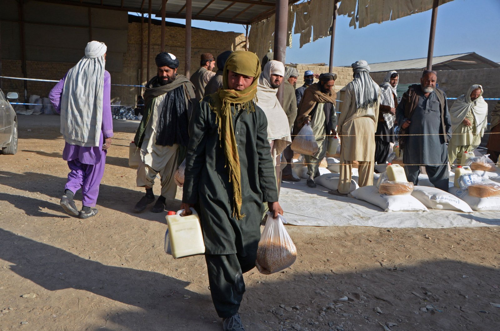 An Afghan boy carries food packets being distributed by the members of the World Food Programme (WFP) to families in need in Kandahar, Afghanistan, Dec. 23, 2021. (AFP Photo)