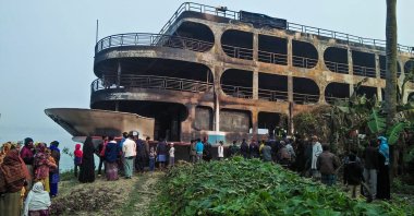 Villagers look at a burnt-out ferry after it caught on fire killing at least 39 people in Jhakakathi, 250 kilometers (160 miles) south of Dhaka, Bangladesh, Dec. 24, 2021. (Photo by AFP)