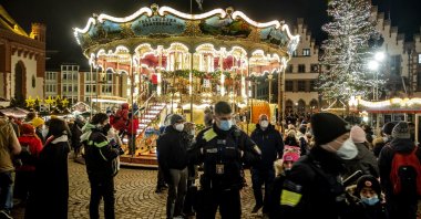 German police officers walk past a merry-go-round on the final day of the Christmas market in Frankfurt, Germany, Dec. 22, 2021. (AP Photo)