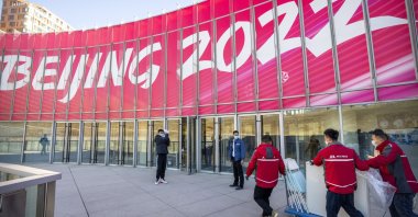 Workers in front of a commercial plaza at the Winter Olympic Village in Beijing, China, Dec. 24, 2021. (AP Photo)
