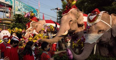 Mahouts and their elephants hand out balloons to children during Christmas celebrations at the Jirasart Witthaya school in Ayutthaya, Thailand, Dec. 24, 2021. (AFP Photo)