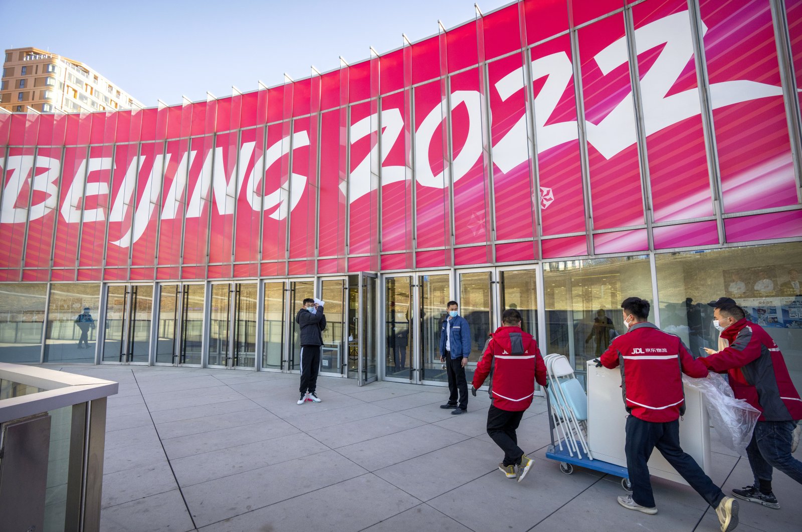 Workers in front of a commercial plaza at the Winter Olympic Village in Beijing, China, Dec. 24, 2021. (AP Photo)