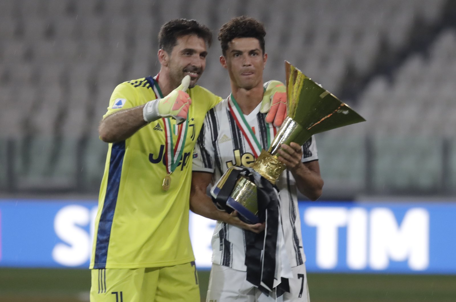 Juventus' Cristiano Ronaldo, right, and Juventus' goalkeeper Gianluigi Buffon hold the trophy as Juventus players celebrate winning an unprecedented ninth consecutive Italian Serie A soccer title, at the end of the a Serie A soccer match between Juventus and Roma, at the Allianz stadium in Turin, Italy, Saturday, Aug.1, 2020. (AP Photo/Luca Bruno)