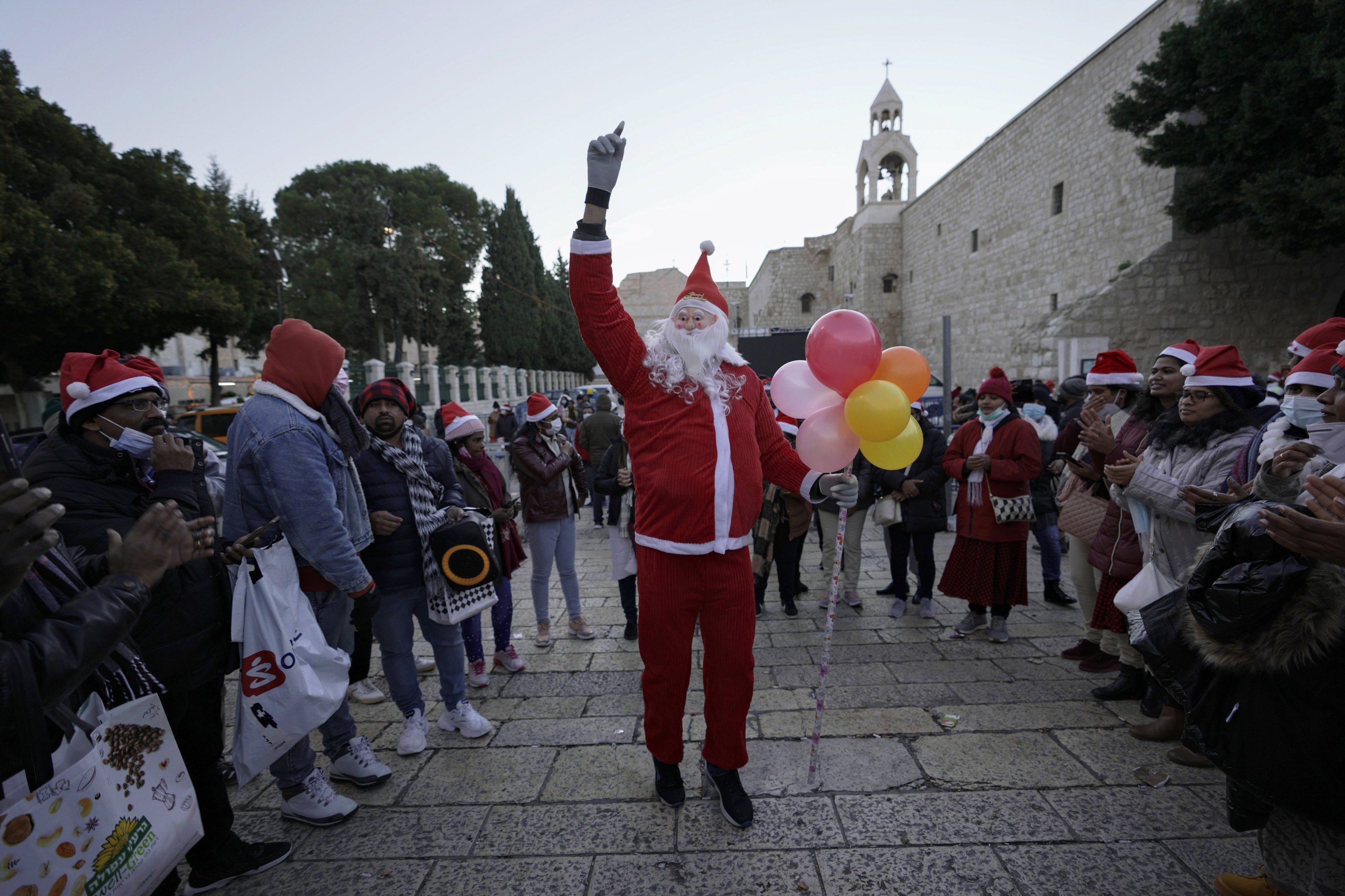 A man dressed as Santa Claus dances outside the Church of the Nativity, traditionally believed to be the birthplace of Jesus Christ, on Christmas Day in the West Bank city of Bethlehem, Palestine, Dec. 25, 2021. (AP Photo)