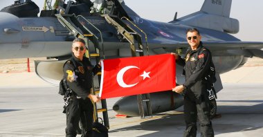 Two members of SOLOTÜRK, the Turkish Air Forces Command&#039;s aerobatics team, holding a Turkish flag in front of the team&#039;s F-16, Ankara, Turkey, Dec. 25, 2021.