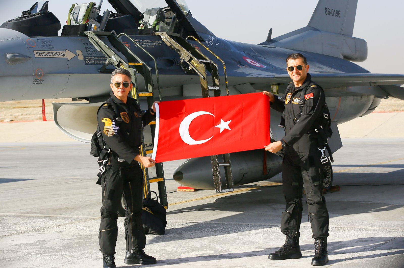 Two members of SOLOTÜRK, the Turkish Air Forces Command&#039;s aerobatics team, holding a Turkish flag in front of the team&#039;s F-16, Ankara, Turkey, Dec. 25, 2021.