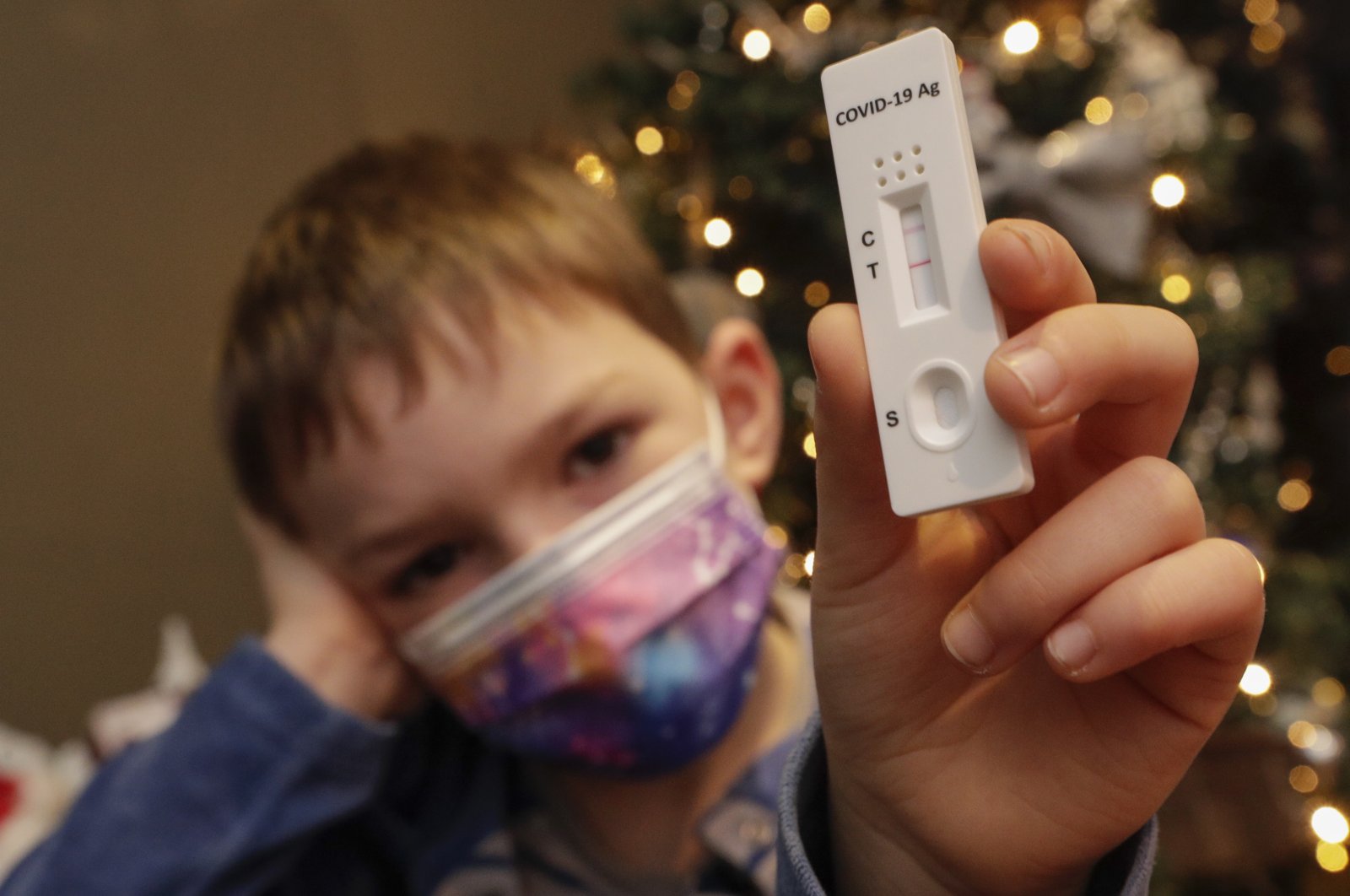 A child poses with a positive rapid COVID-19 antigen test next to a Christmas tree in Namur, Belgium, Dec. 24, 2021. (EPA Photo)