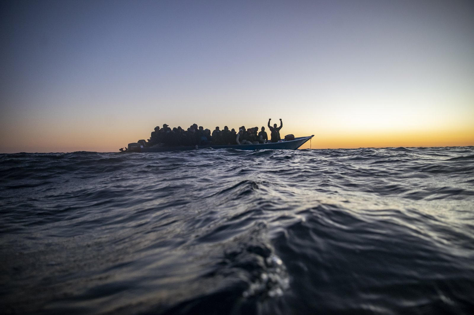 Migrants and refugees of various African nationalities wait for assistance aboard an overcrowded wooden boat in the Mediterranean Sea 122 miles off the coast of Libya as aid workers on the Spanish search and rescue vessel Open Arms approach, Feb. 12, 2021. (AP Photo)