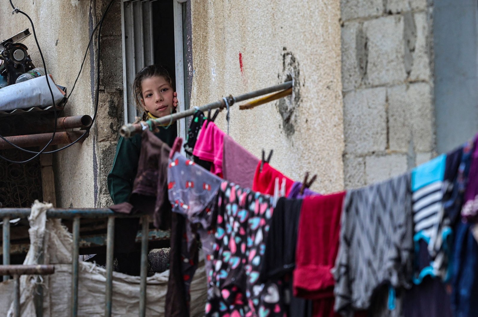 A young Palestinian girl is pictured as laundry hangs to dry at her home in Beit Lahia in the northern Gaza Strip, on Dec. 23, 2021. (AFP)