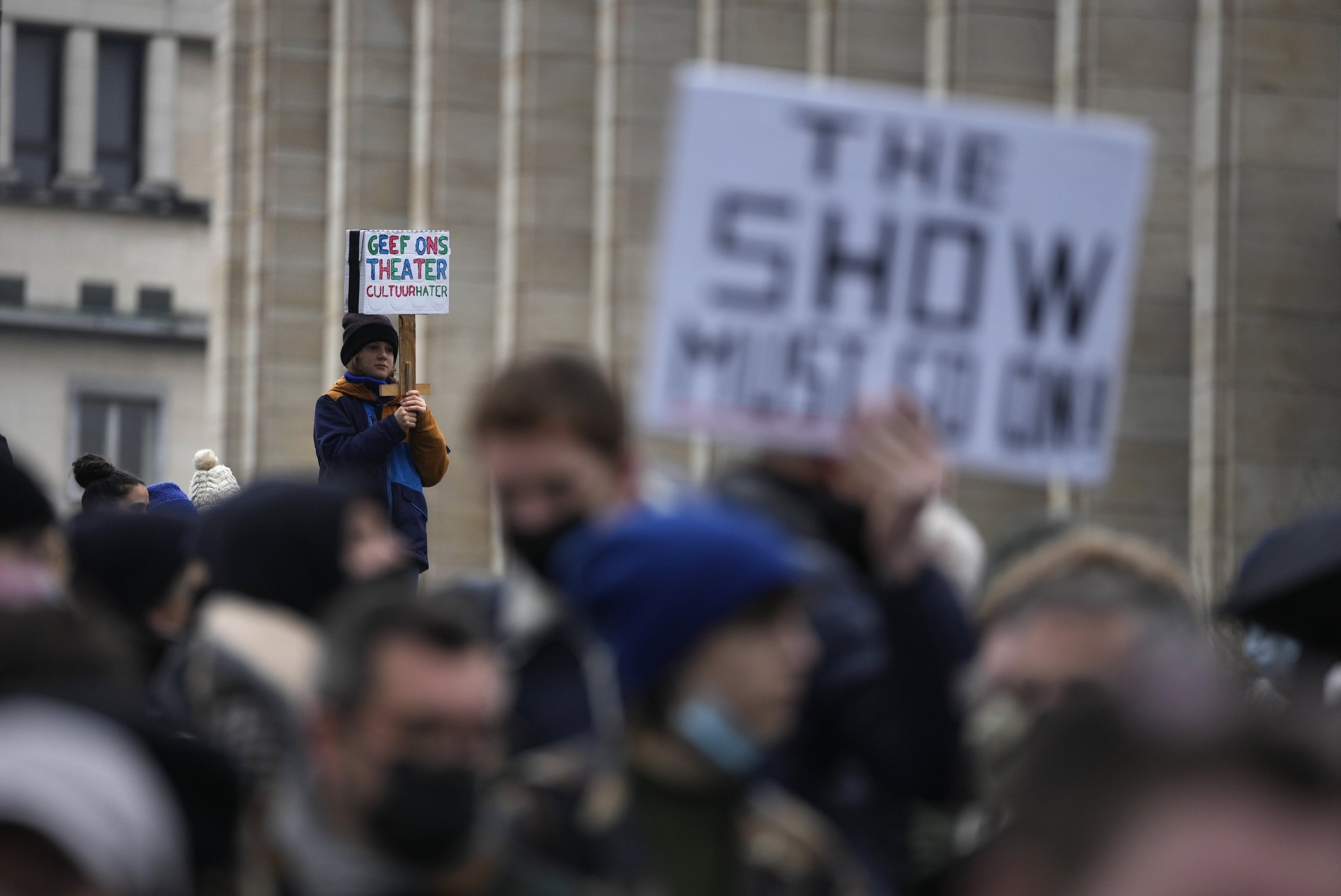A boy holds a sign that reads "Give us Theatre, culture haters" as he protests with other artists during a demonstration in Brussels on Sunday, Dec. 26, 2021. (AP)