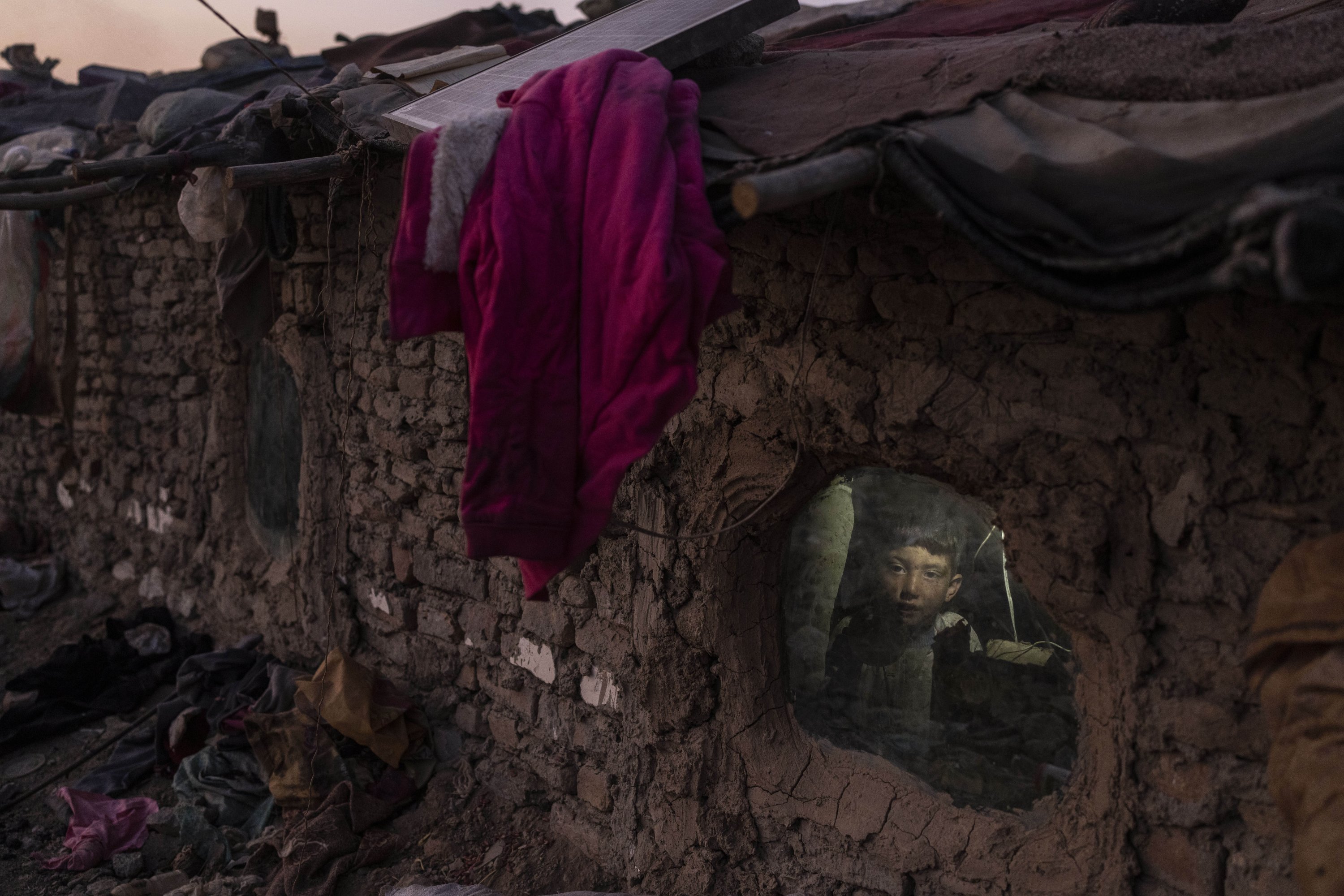 A child looks out of a window of his home in a neighborhood where many internally displaced people have been living for years, in Kabul, Afghanistan, Dec. 7, 2021. (AP Photo)