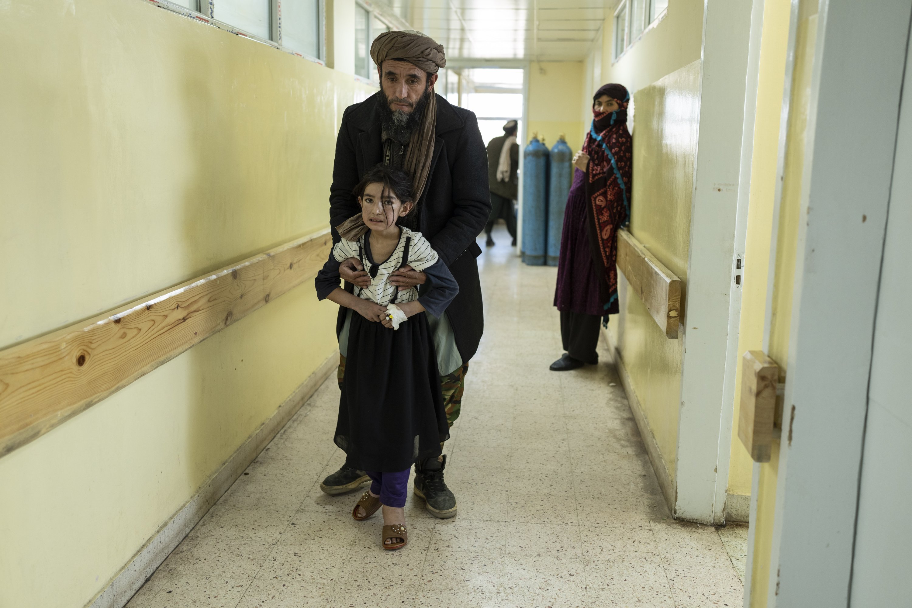 Seorang gadis berjalan dengan bantuan ayahnya di Rumah Sakit Anak Indira Gandhi di Kabul, Afghanistan, 8 Desember 2021. (AP Photo)