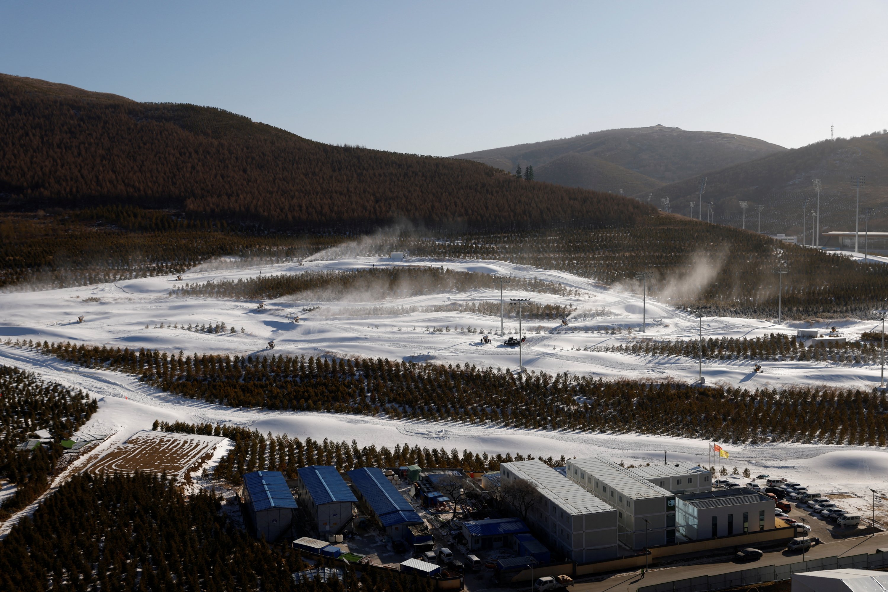 Trees and snow guns operating are seen on slopes near the National Ski Jumping Centre during a government-organized media tour to Beijing 2022 Winter Olympics venues, Zhangjiakou, China, Dec. 21, 2021. (Reuters Photo)