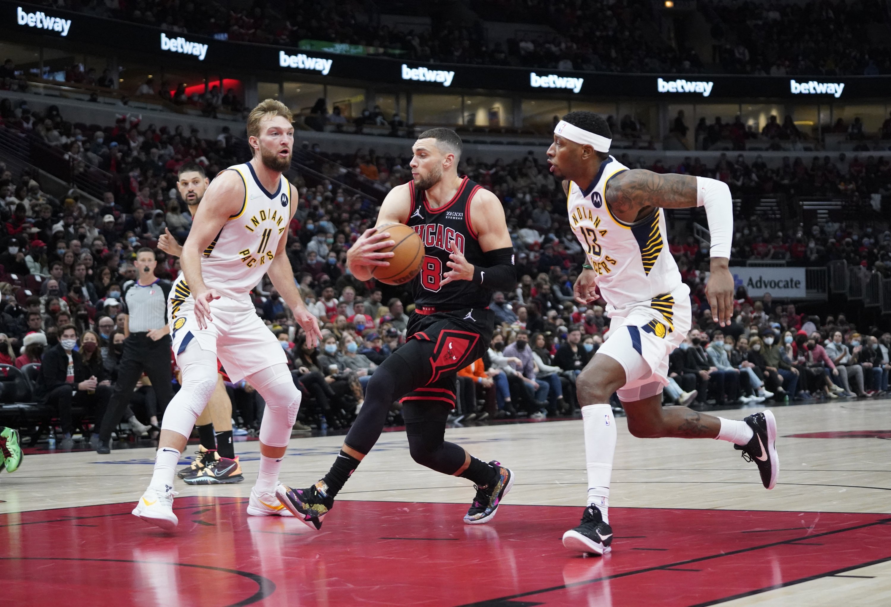 Penjaga banteng Zach LaVine (tengah) menabrak penyerang Pacers Domantas Sabonis (kiri) selama pertandingan NBA, Chicago, Illinois, AS, 26 Desember 2021. (Foto Reuters)