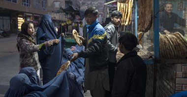A man disributes bread to Afghan women outside a bakery in Kabul, Afghanistan, Dec, 2, 2021. (AP Photo)