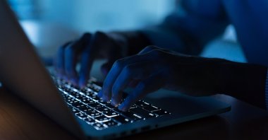 Man types on a laptop in the darkness in this undated file photo. (Shutterstock File Photo)