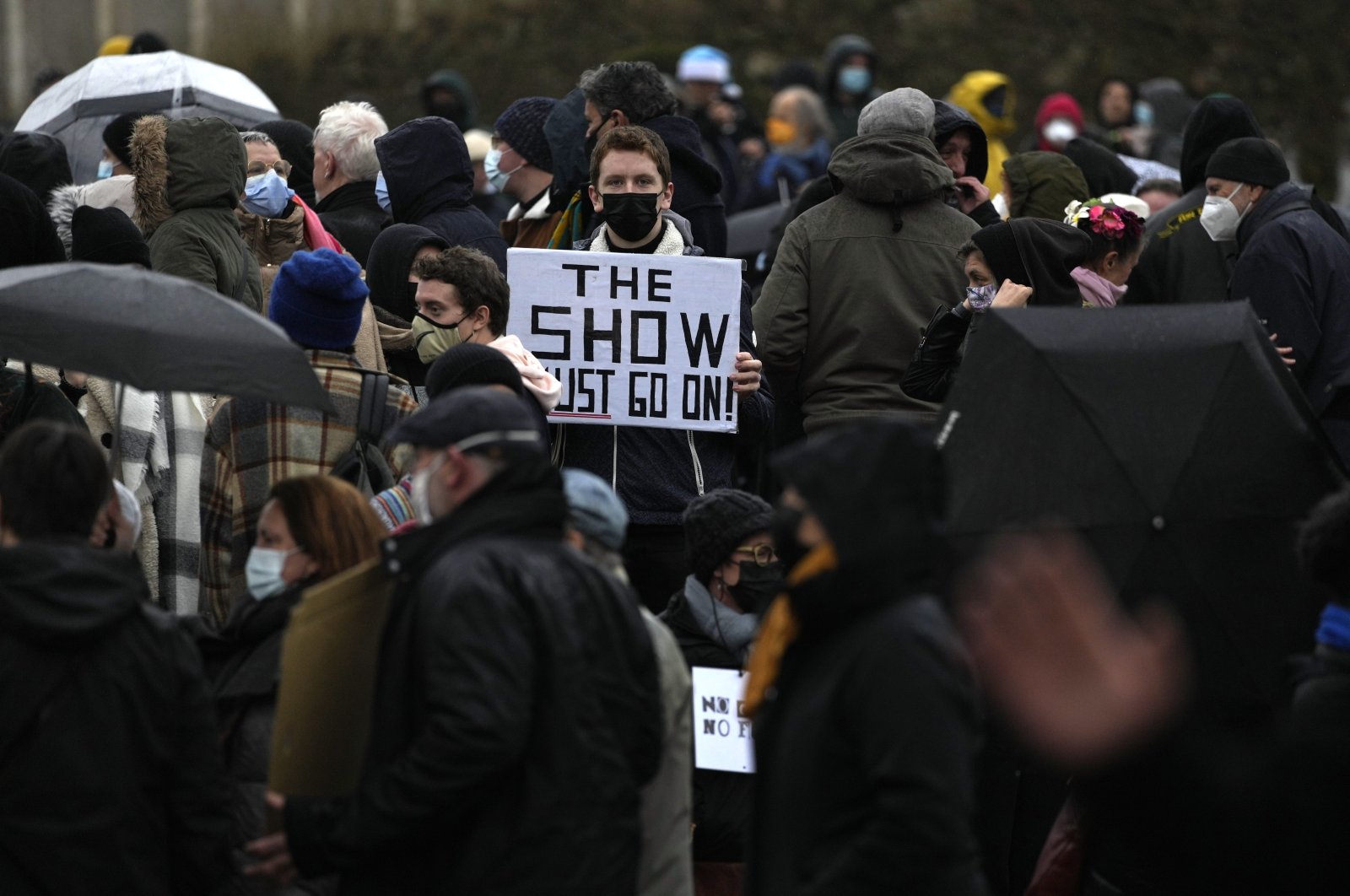 A man holds a sign that reads "The show must go on" as he protests with other artists during a demonstration in Brussels on Sunday, Dec. 26, 2021.(AP)
