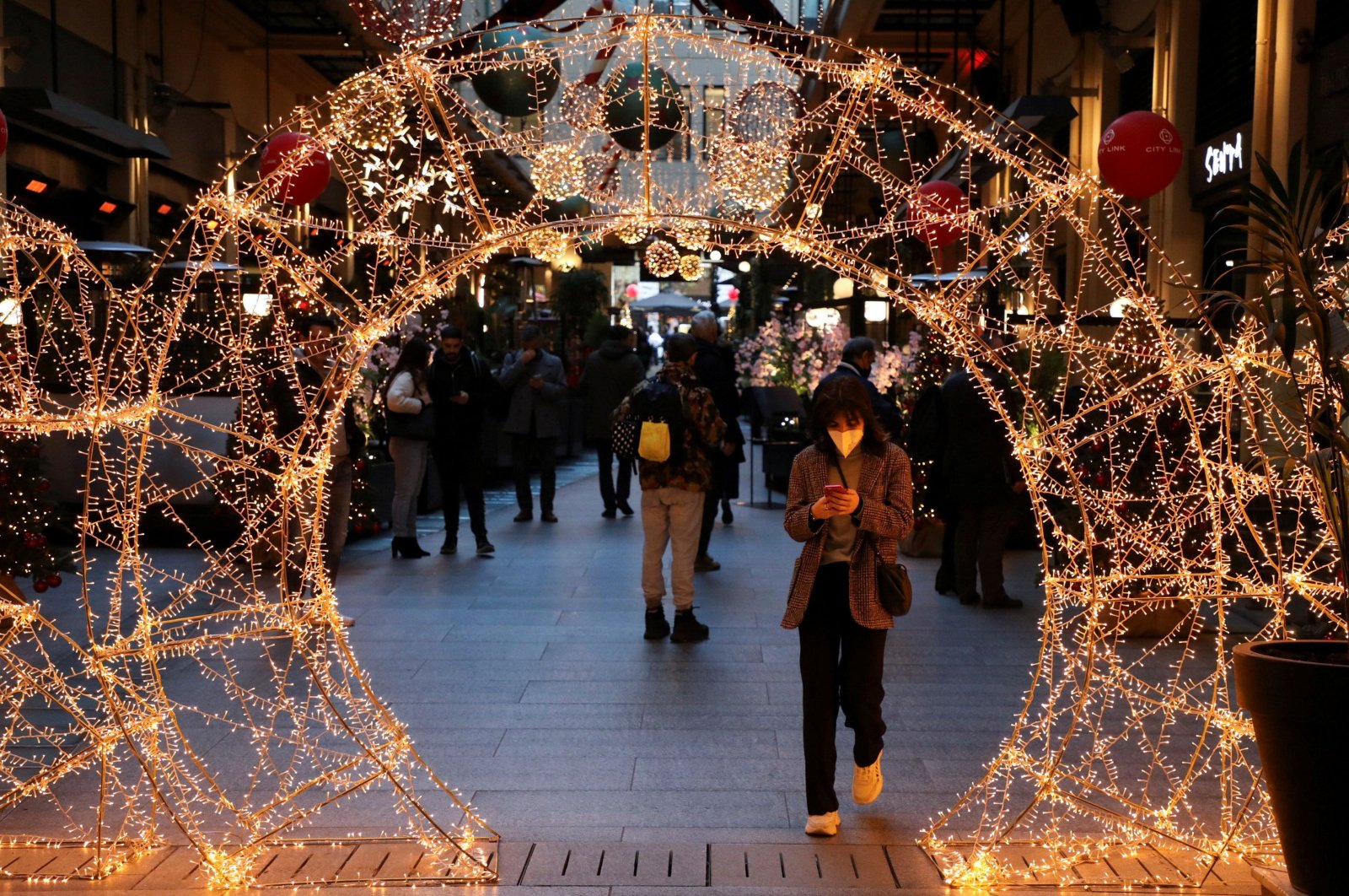 A person wearing a protective face mask makes her way through Christmas decorations as Greece bans public Christmas and New Year&#039;s Eve festivities and mandates mask-wearing in open spaces to help curb the spread of the omicron coronavirus variant, in Athens, Greece, Dec. 23, 2021. (Reuters Photo)
