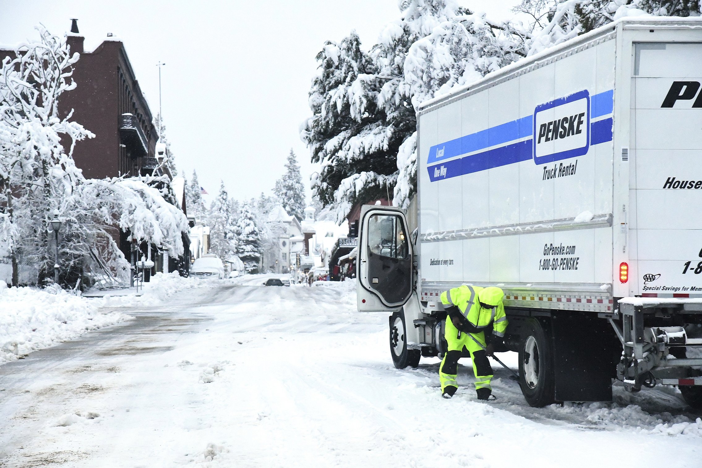 A Penske truck driver awaits the arrival of tire chains to get himself unstuck, along the Broad Street overpass, in Nevada City, California, U.S., Dec. 27, 2021. (AP Photo)