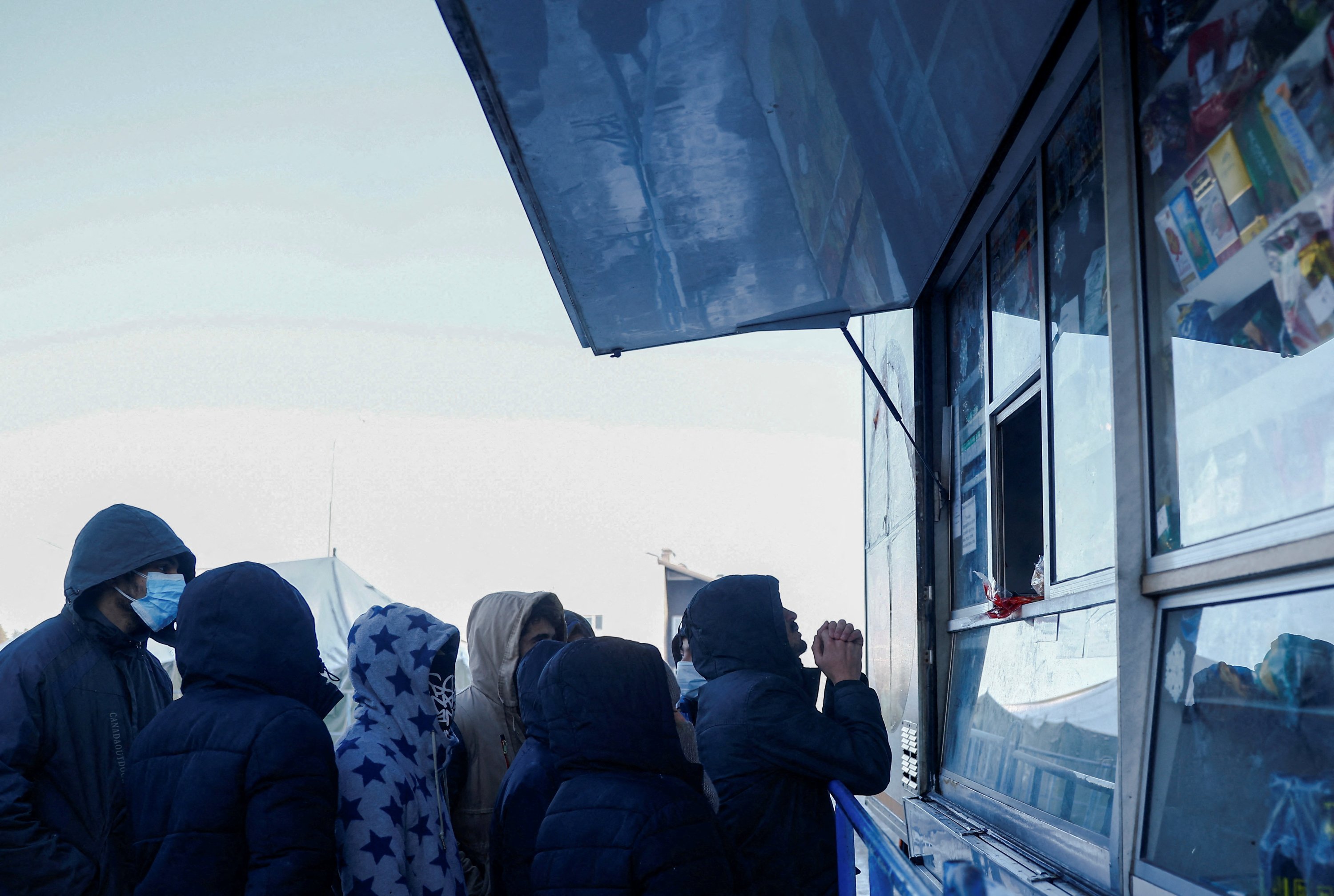 Migrants queue in front of a mobile food shop outside the transport and logistics centre Bruzgi on the Belarusian-Polish border, in the Grodno region, Belarus December 22, 2021. (Reuters Photo)