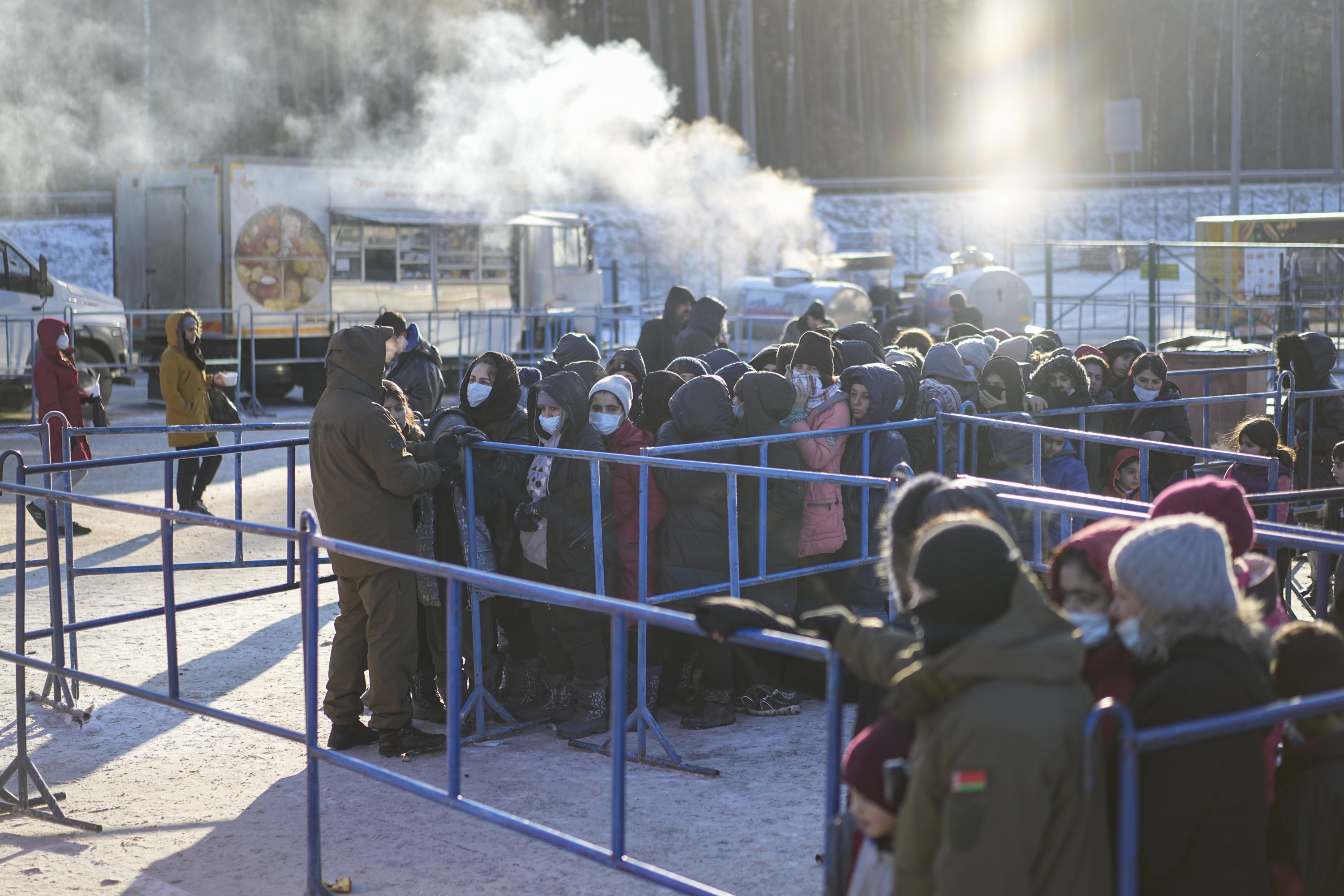 Migrants queue to receive hot food at the "Bruzgi" checkpoint logistics center at the Belarus-Poland border near Grodno, Belarus, Dec. 22, 2021.  (AP Photo)