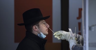 An Israeli health worker tests an unvaccinated ultra-Orthodox Jewish seminary student for COVID-19 at a coronavirus testing center in West Jerusalem, Israel, Dec. 22, 2021. (AP Photo)