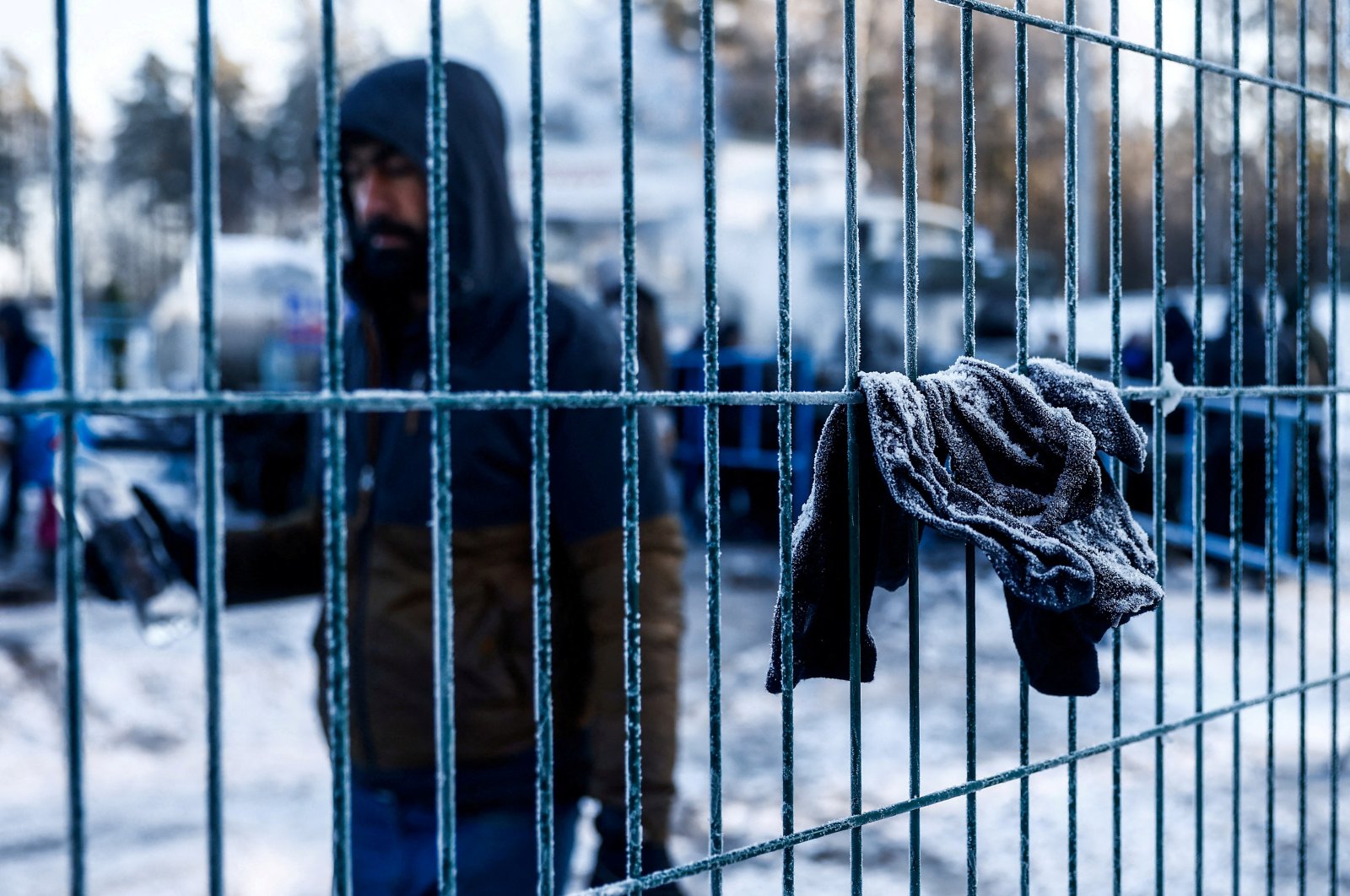 A migrant walks past frozen clothings hanging on a fence outside the transport and logistics centre Bruzgi on the Belarusian-Polish border, in the Grodno region, Belarus December 22, 2021. (Reuters Photo)