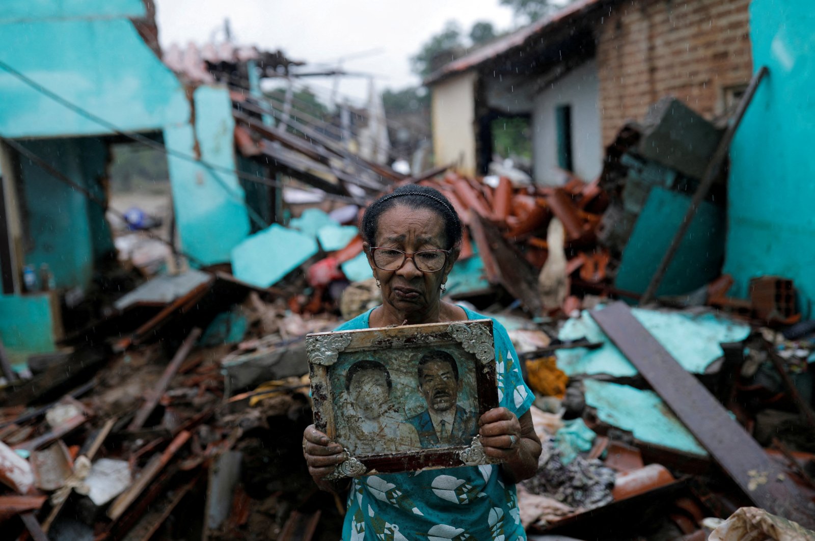 Vitoria Rocha, 81, poses with a picture of her parents that she salvaged from the rubble of her home of almost 40 years after it was destroyed by floods, Itambe, Bahia, Brazil, Dec. 28, 2021. (Reuters File Photo)
