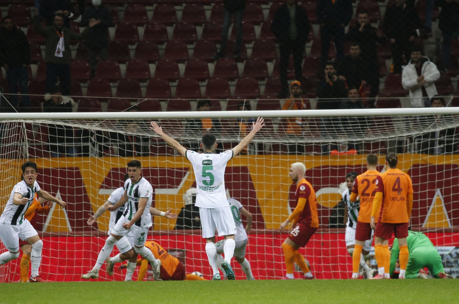 Denizlispor players, in white and green jerseys, celebrate while Galatasaray players look dejected after the Ziraat Turkish Cup match in Istanbul, Turkey, Dec. 28, 2021. (DHA Photo)