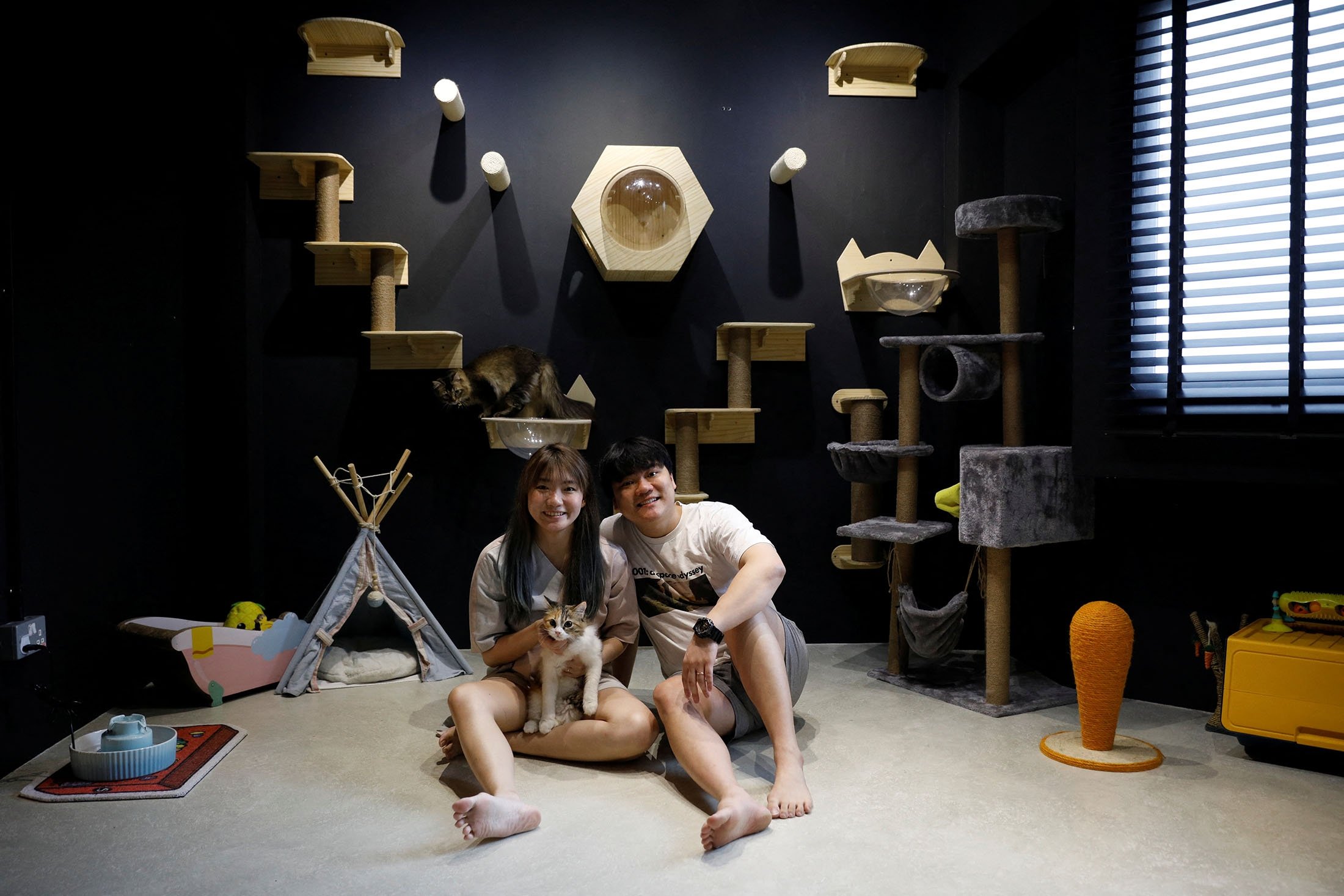 Signmaker Ruvyn Tng, 31, and his wife, home baker Phoebe, 28, pose with their cats Kaala and Mocha in their cat cafe-inspired, 21-year-old resale four-room public housing apartment in Singapore, Aug. 30, 2021. (Reuters Photo)