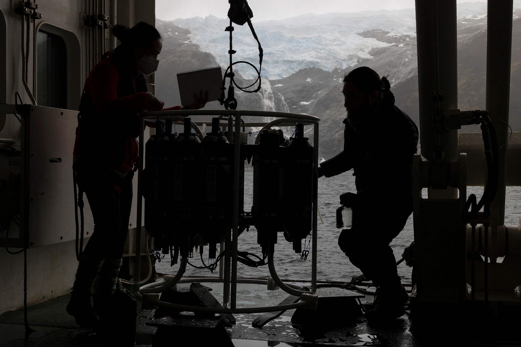 Marine biologist Emilio Alarcon (R) takes water collected by water sampling devices from the sea in the region of Magallanes, Chile, Nov. 28, 2021. (AFP Photo)