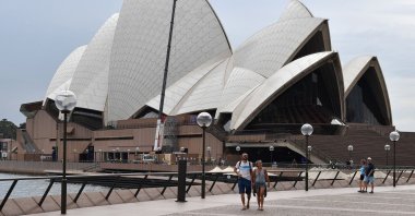 Few people walk along Circular Quay outside the Opera House in Sydney  as people stay away due to restrictions to stop the spread of the COVID-19 coronavirus outbreak, Australia, March 25, 2020. (AFP Photo)