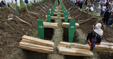 Bosniak people walk among the graves of victims of the Srebrenica massacre during a memorial ceremony in Srebrenica, Bosnia-Herzegovina, Friday, July 11, 2014. (AP Photo)
