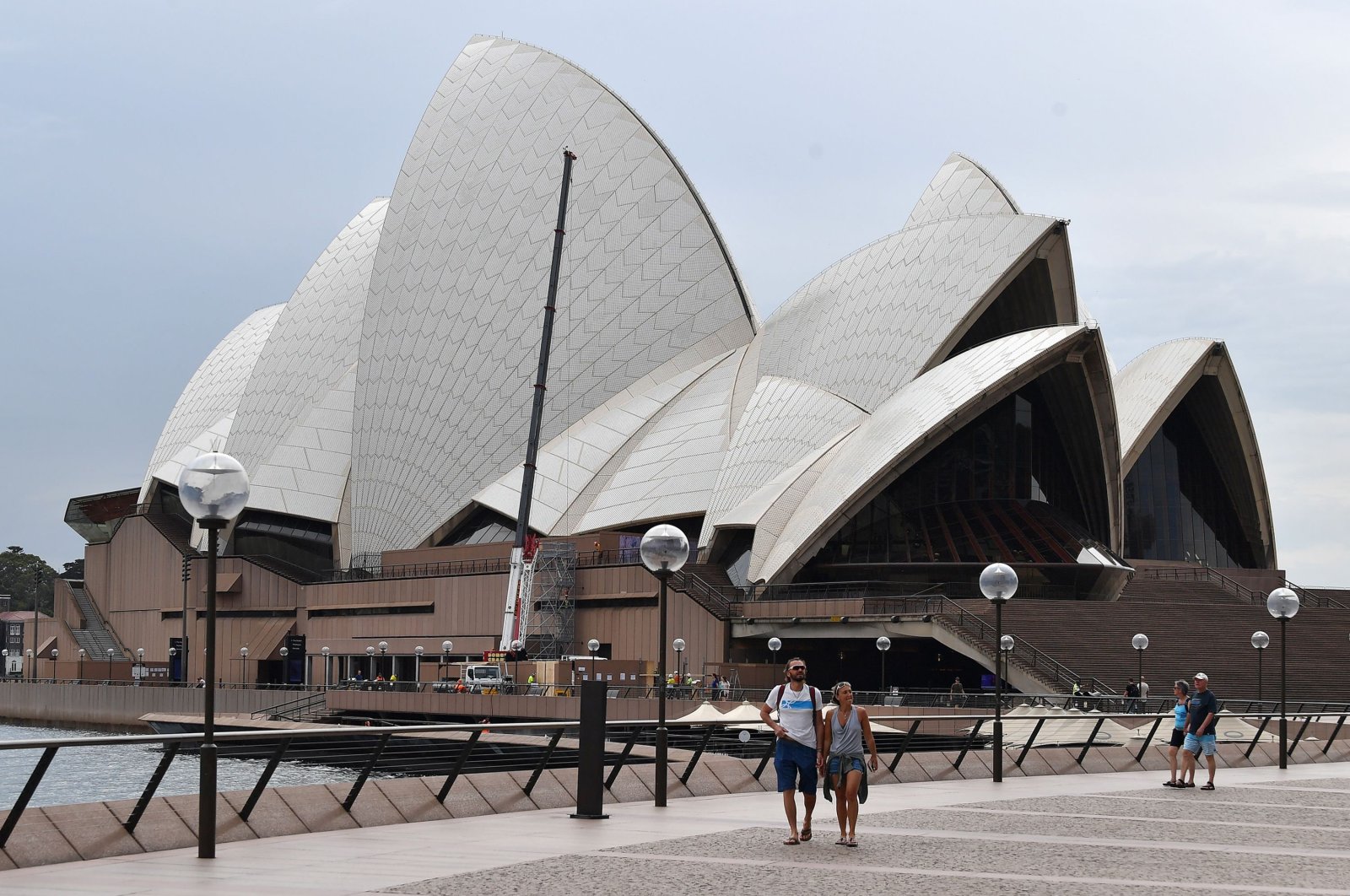 Few people walk along Circular Quay outside the Opera House in Sydney  as people stay away due to restrictions to stop the spread of the COVID-19 coronavirus outbreak, Australia, March 25, 2020. (AFP Photo)