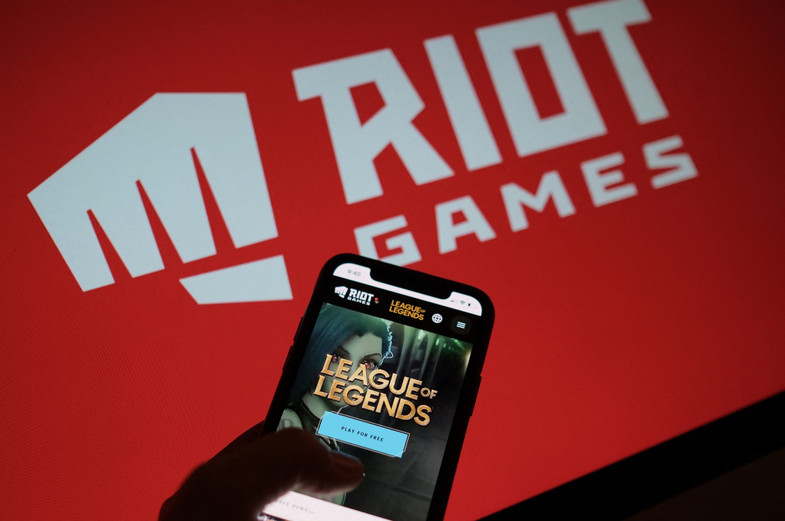 The game League of Legends is seen on a smartphone screen in front of the Riot Games logo in Los Angeles, California, U.S., Dec. 27, 2021. (AFP Photo)