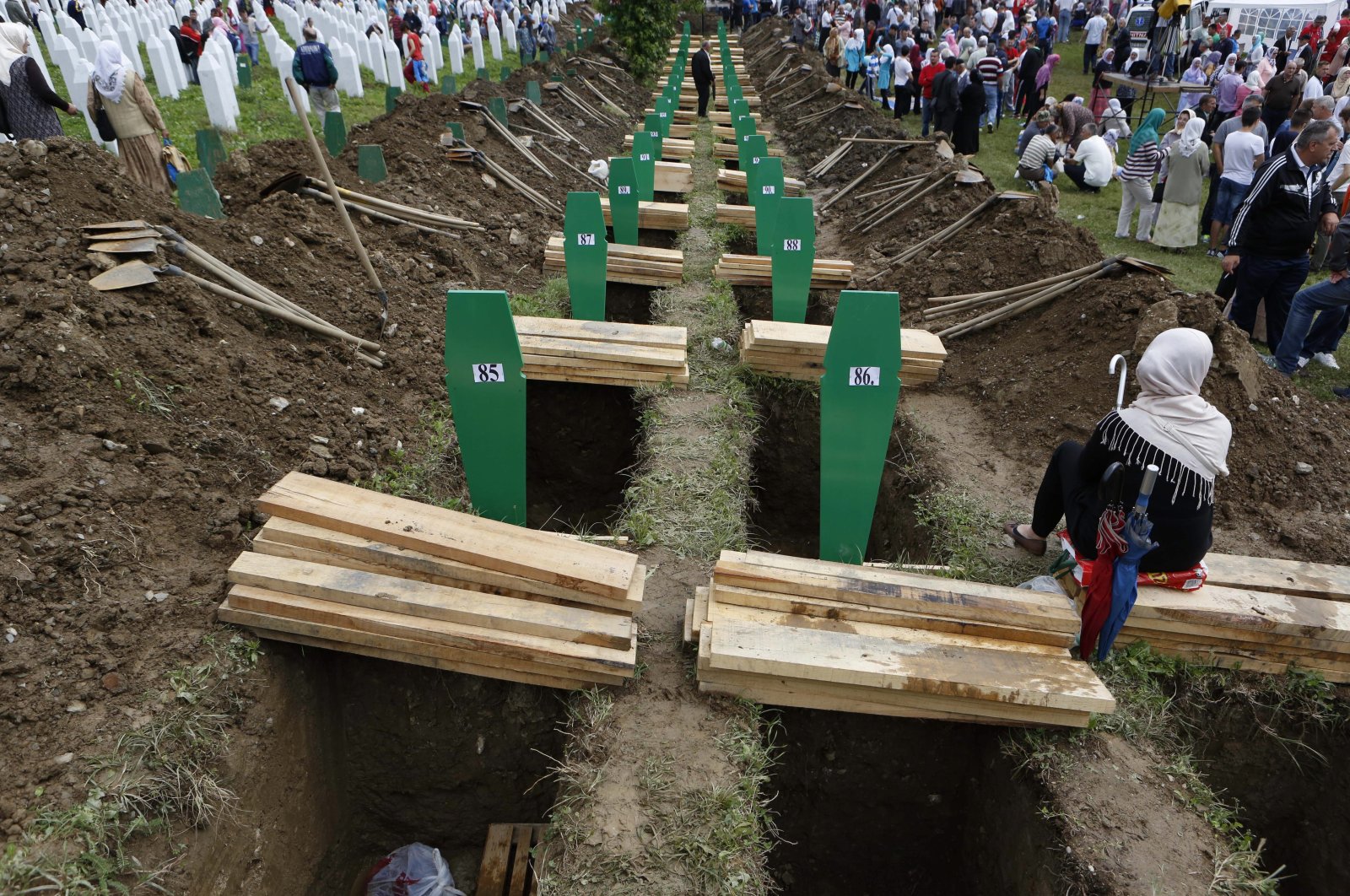 Bosniak people walk among the graves of victims of the Srebrenica massacre during a memorial ceremony in Srebrenica, Bosnia-Herzegovina, Friday, July 11, 2014. (AP Photo)