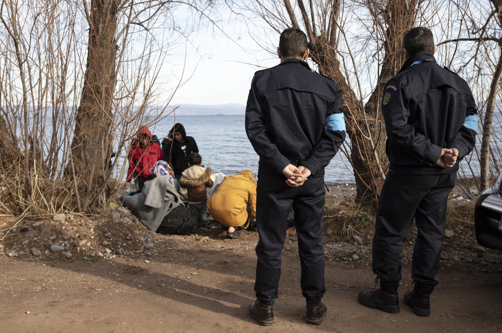 Frontex border officers stand by migrants on the shore near the village of Skala Sikamineas on the island of Lesbos, Greece, March 1, 2020. (Getty Images)