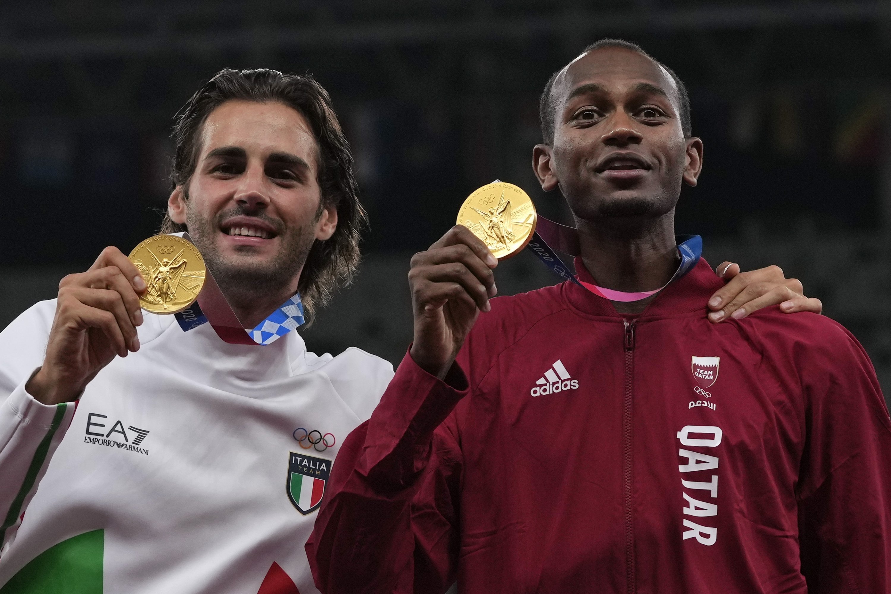Atlet Italia Gianmarco Tamberi (kiri) dan Qatar Mutaz Barshim (kanan) setelah berbagi medali emas lompat tinggi di Olimpiade Tokyo 2020, Tokyo, Jepang, 2 Agustus 2021. (AP Photo)